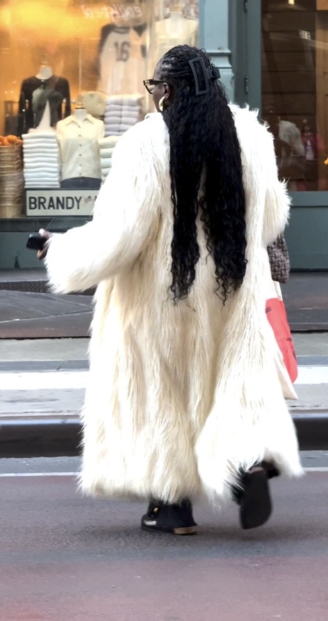 Long white shaggy faux fur coat with black dreadlocks and a hair clip.