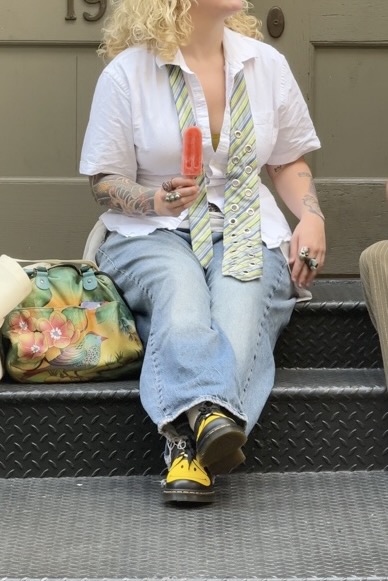 White collared shirt, baggy jeans, green striped tie with grommets, yellow combat boots, and popsicle.