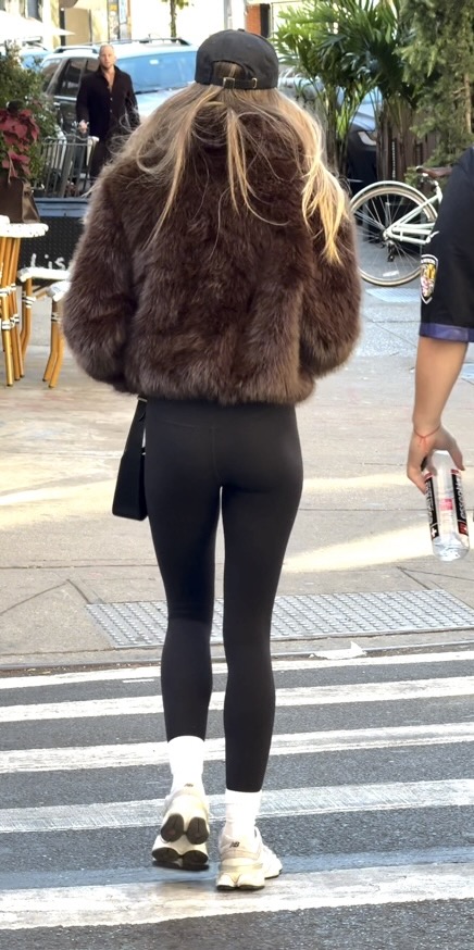 Blonde woman in brown fur coat, black leggings, white socks, and white sneakers.
