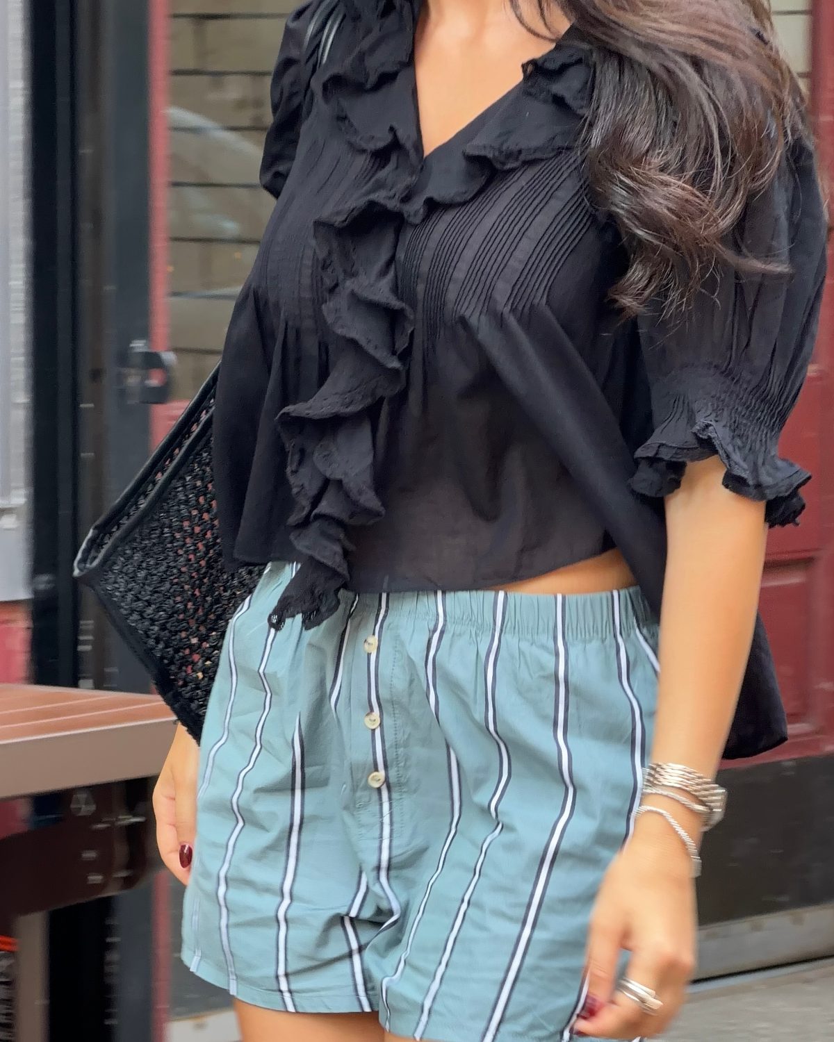 Black ruffled blouse with puff sleeves and aqua striped shorts.
