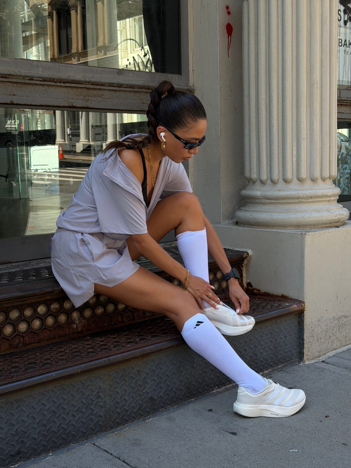Gray romper, black bra, white knee-high socks, and white sneakers on a city street.