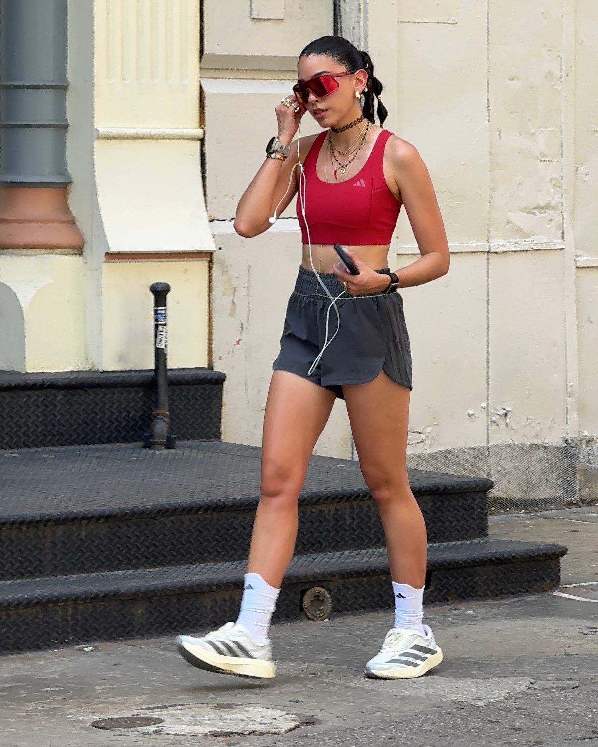 Red Adidas sports bra with dark gray shorts, white sneakers, and red sunglasses.